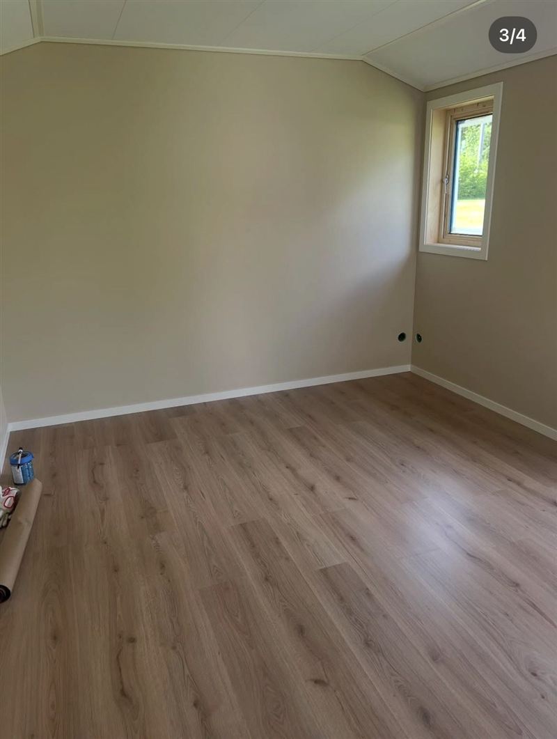 Insidan av friggeboden med färdigt laminatgolv, målade väggar och fönster