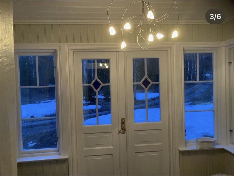 Insidan av glasverandan med vita paneldörrar och panelade väggar