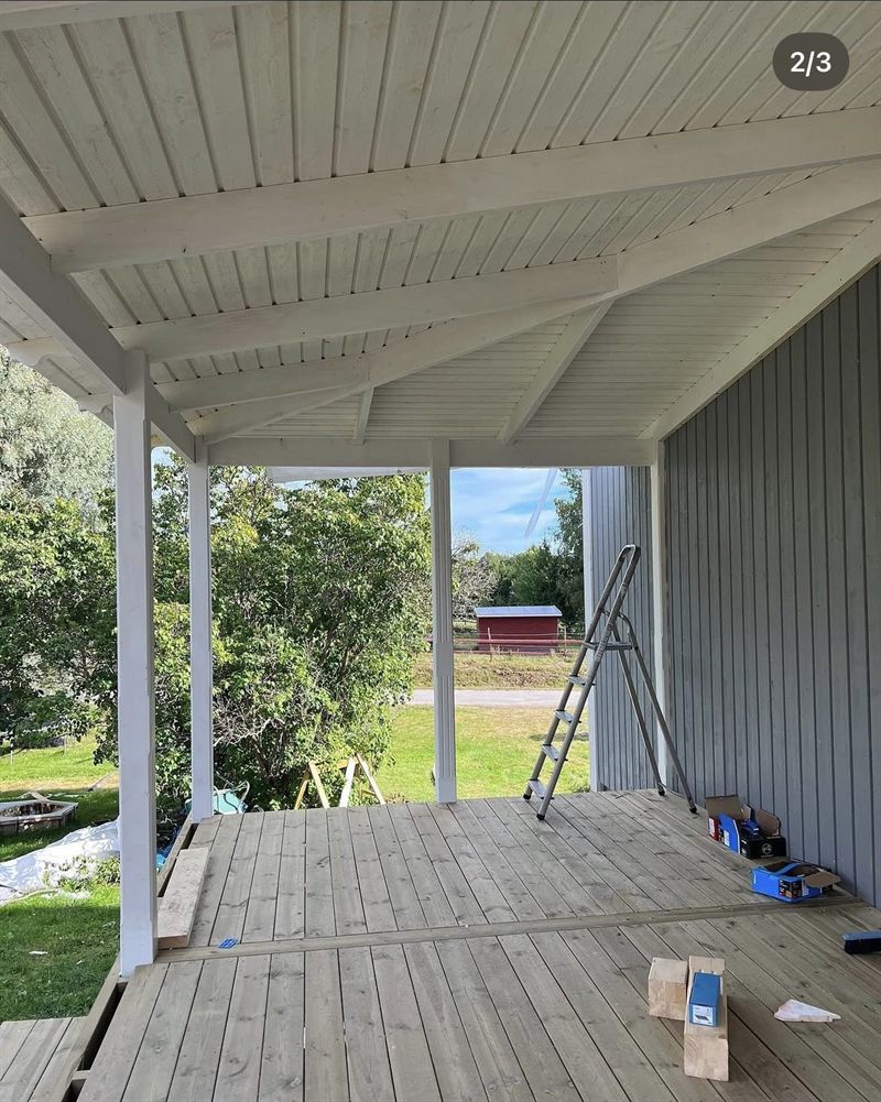 Samma veranda inifrån med färdigt undertak, synliga takbjälkar och trall på golvet
